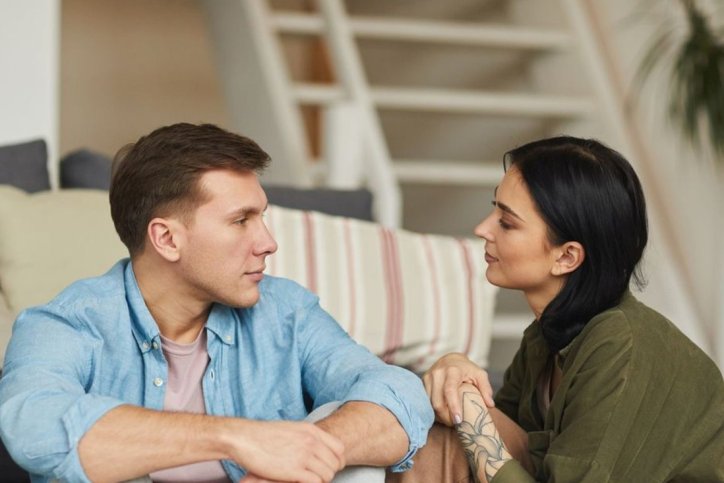 Ein Paar unterhält sich sitzend im Wohnzimmer. der Mann leidet unter Prosopagnosie.