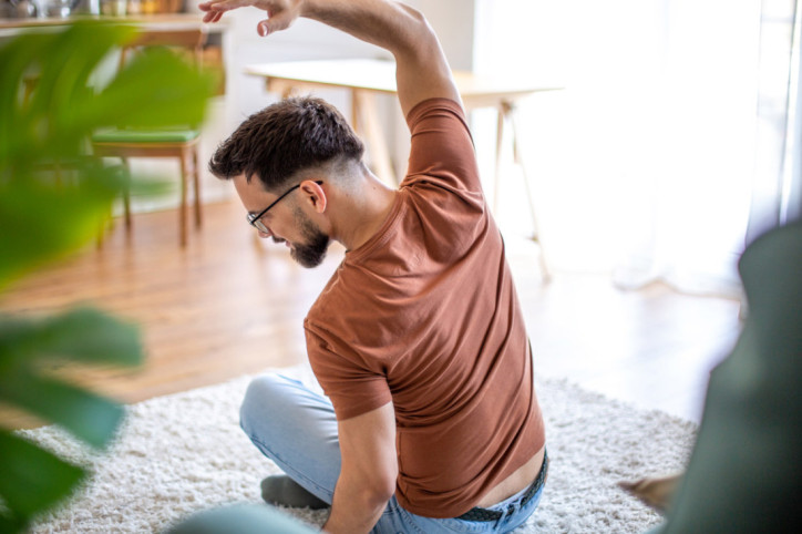 Ein junger Mann beugt Hexenschuss mit Dehnübungen vor