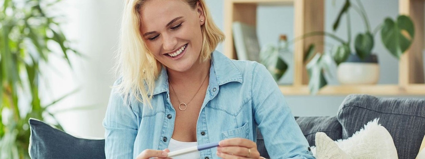 Eine Frau freucht sich nach positivem Textergebnis über ihre Fruchtbarkeit
