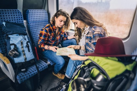 Zwei Frauen über einer Landkarte im Zug.