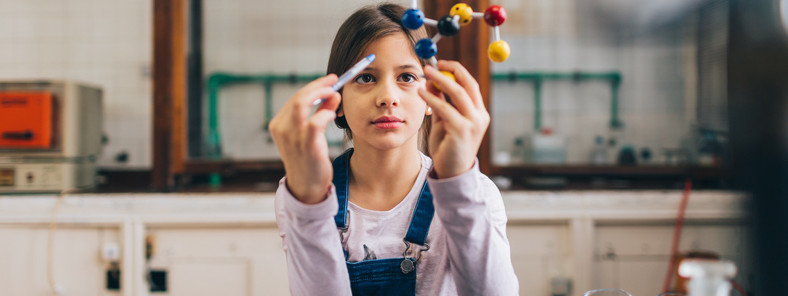 10-jähriges Mädchen mit Molekülmodell im Chemie-Klassenraum