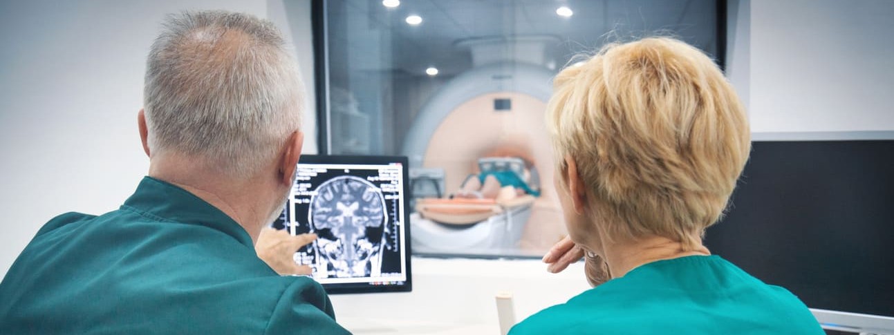 Zwei Spezialisten der MVZ Radiologie Saalekreis schauen auf zwei Bildschirme mit einem MRT.