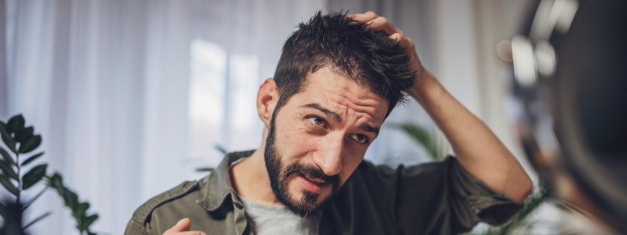 Ein Mann fasst sich an seine juckende Kopfhaut.