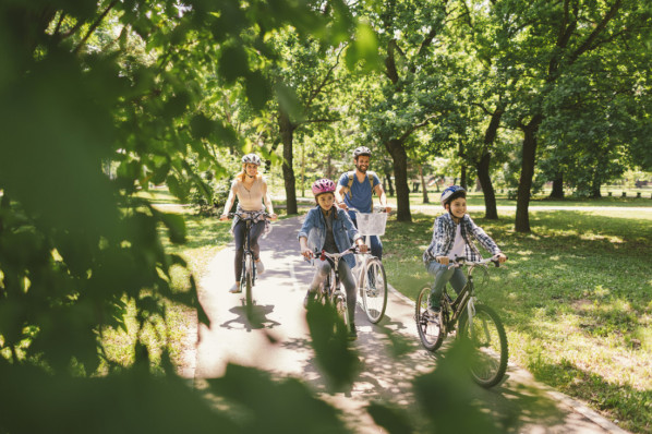 Family riding bicycle in the public park together. Cycling and enjoying the sunny day