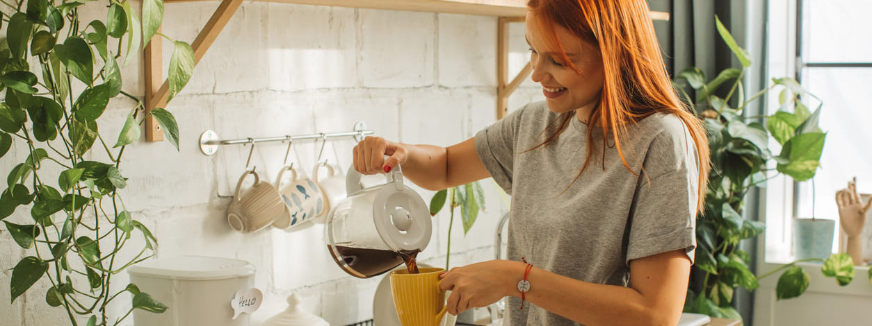 Eine Frau gießt sich eine Tasse Filterkaffee ein