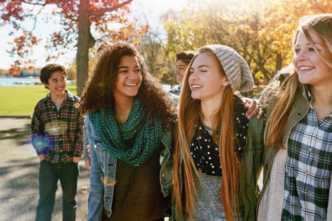 Eine Gruppe von 5 Teenagern fröhlich lächelnd in der Herbstsonne.