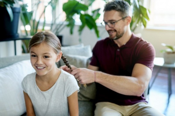 Eine etwa 35 jährige Frau sitzt an einem Schreibtisch. Vor ihr steht ein Festnetztelefon und ein Computer. Sie kneift mit ihrem Zeigefinger und Daumen zwischen die Augen und wirkt gestresst.