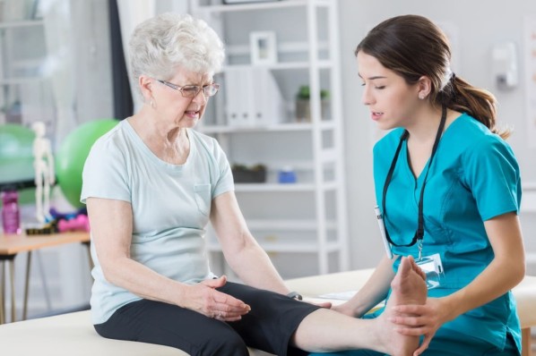 Eine Ärztin untersucht das Bein einer Seniorin mit Verdacht auf Lymphödem