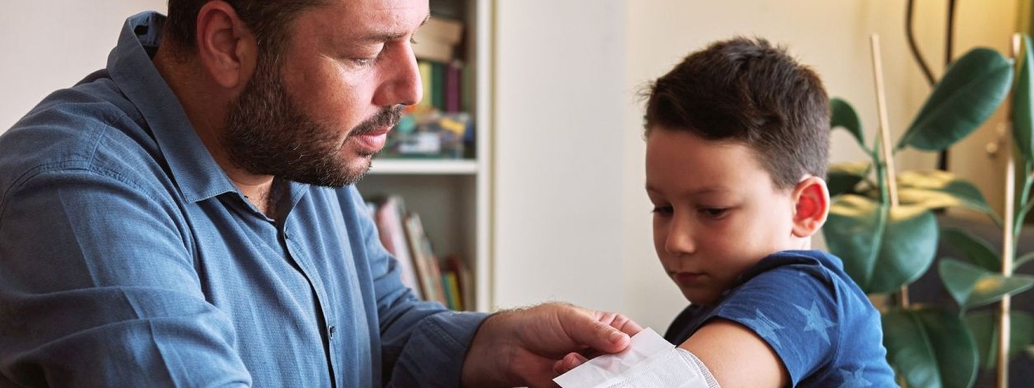 Ein Vater wendet das Wissen aus einem Kinder-Erste-Kurs bei seinem Sohn an