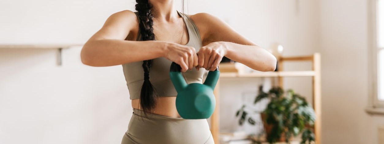 Junge Frau trainiert mit einer Kettlebell.