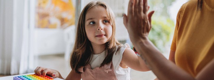 Eine neurodivergentes Mädchen schlägt mit einer Erwachsenen ein