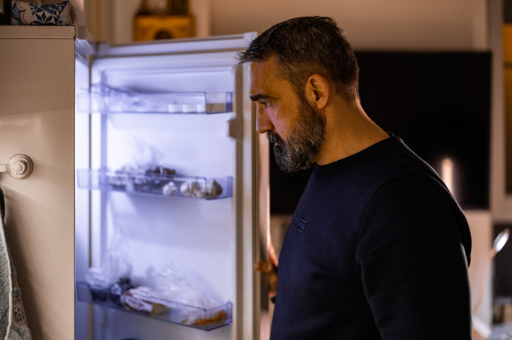 Ein Mann schlafwandelt und schaut nachts starrend in den Kühlschrank.