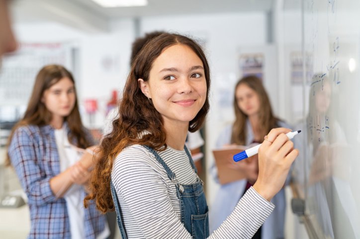 Mädchen im teenageralter schreibt etwas an ein Whiteboard