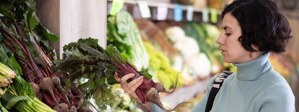 Eine Frau kauft Knollen- und Wurzelgemüse im Supermarkt