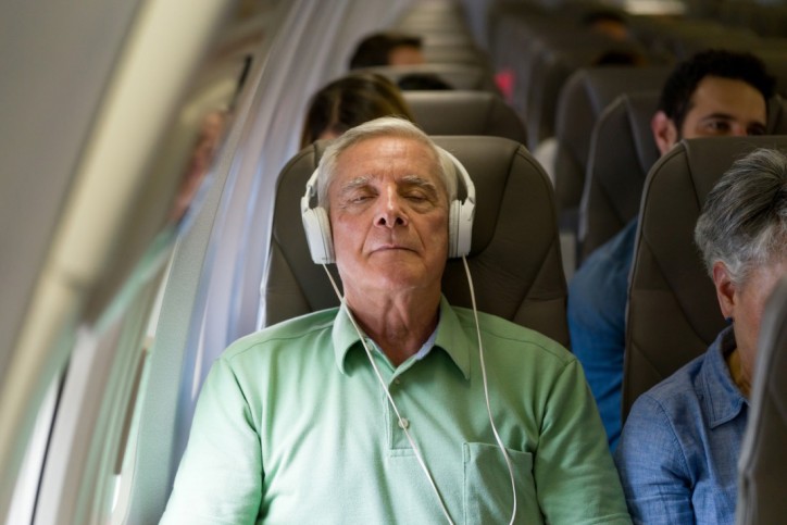 Ein Senior mit Aviophobie hört während des Flugs Musik über Kopfhörer