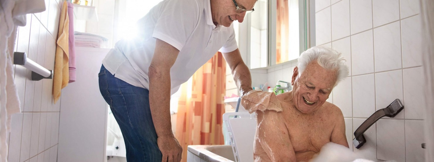 Pfleger hilft einem Senioren beim Waschen