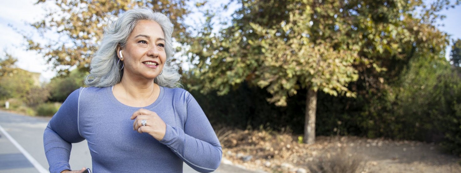 Eine etwa 70-jährige Frau geht auf eine Straße joggen.