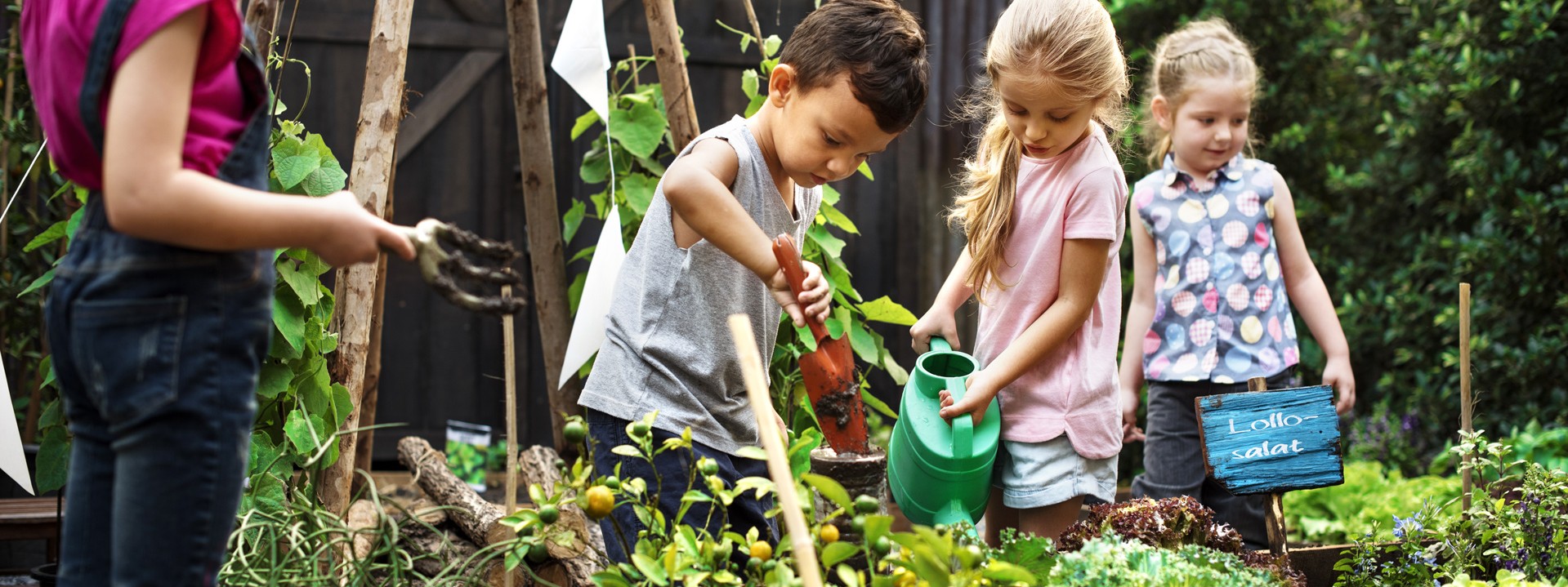 Kinder bei der Gartenarbeit an einem Hochbeet.