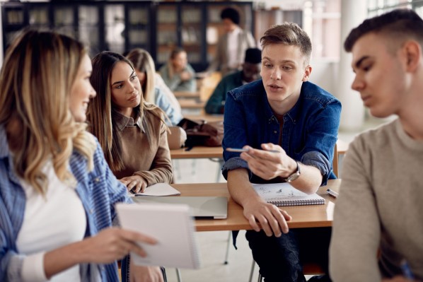 Vier Jugendliche sitzen in der Schule und diskutieren.