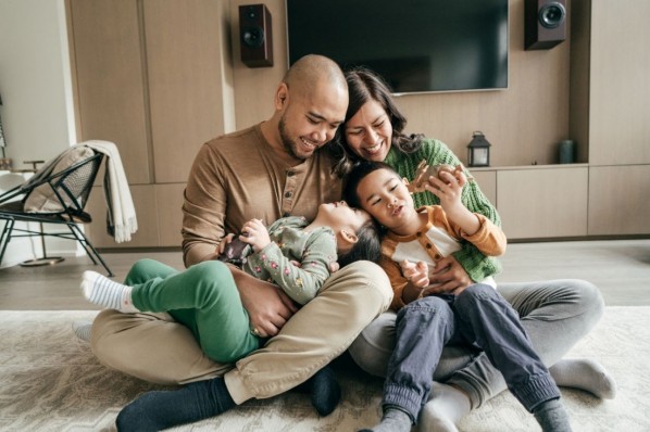 Eine vierköpfige Familie spielt zusammen auf dem Boden im Wohnzimmer.