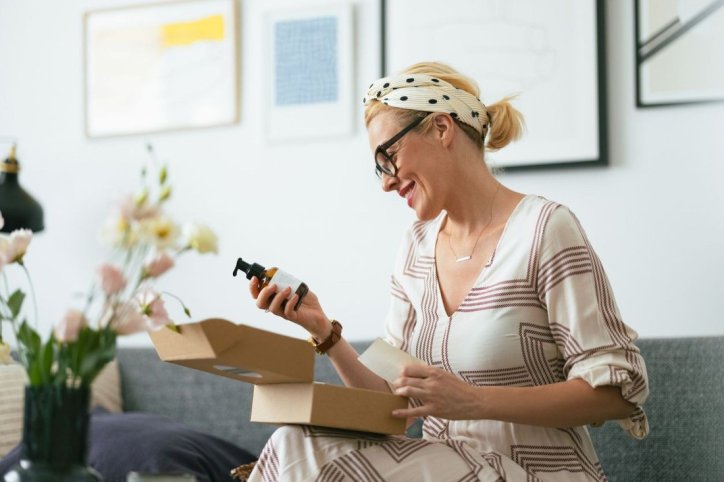 Eine Frau packt ein Paket mit Kollagen-Supplements aus