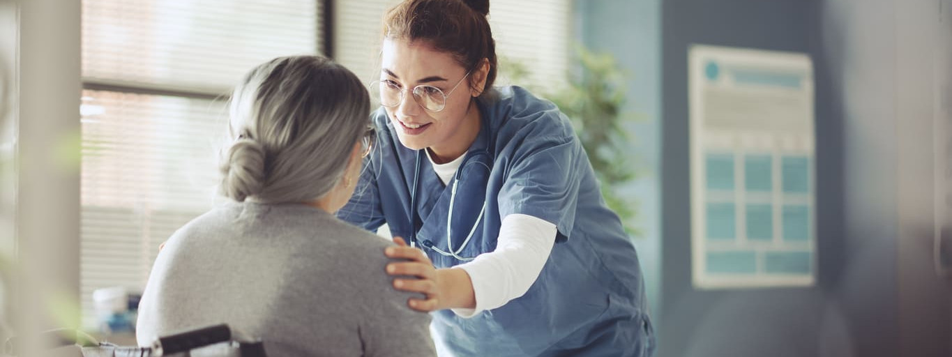 Junge Krankenschwester betreut Seniorin im Rollstuhl