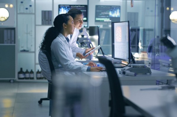 Zwei junge Forscherinnen sitzen im Labor und schauen etwas auf dem Computer an.