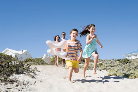 Eine Familie besucht den Strand, die beiden Kinder laufen vorweg