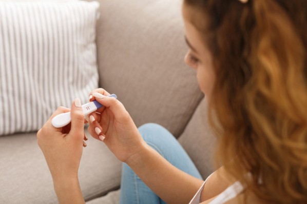 JUnge Frau mit Schwangerschaftstest in der Hand.