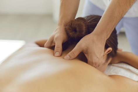 Junge Frau erhält eine Massage im Nackenbereich. 