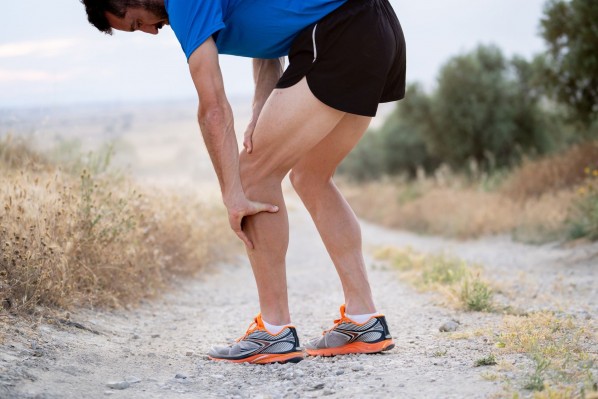 Junger Mann hält sein schmerzendes Knie beim Joggen. 