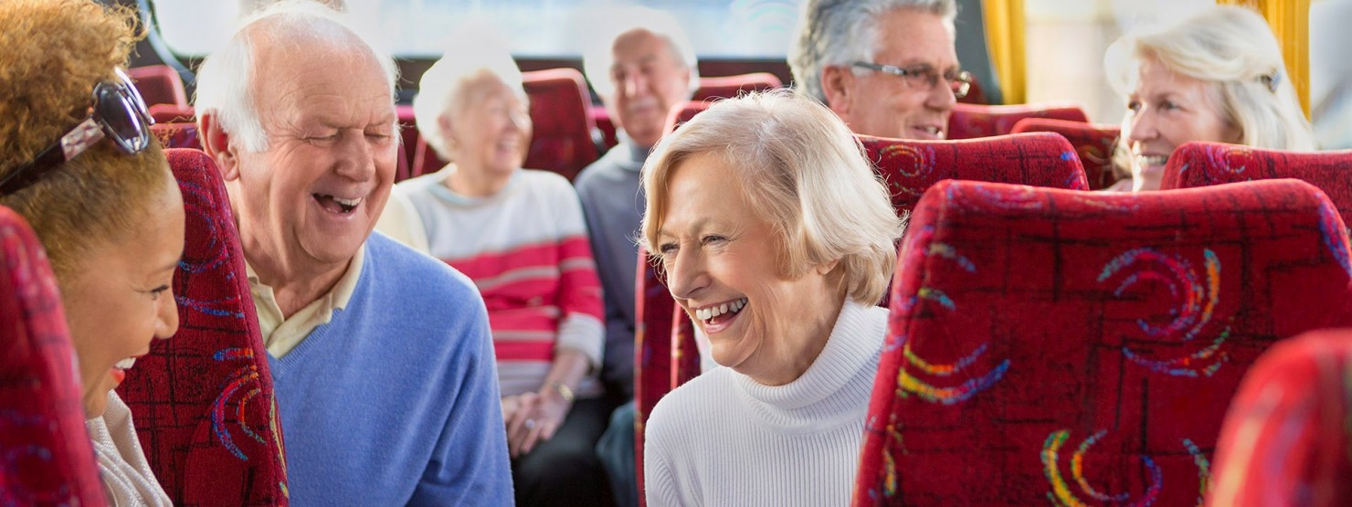 Senioren sitzen fröhlich in einem Reisebus.