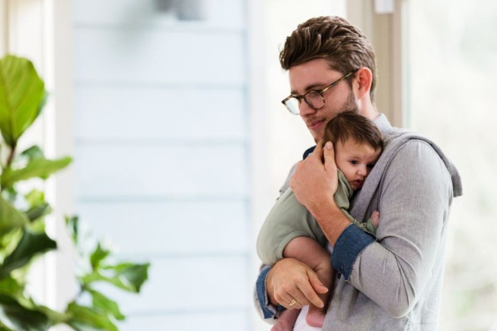 Mann hält sein Baby mit KiSS-Syndrom.