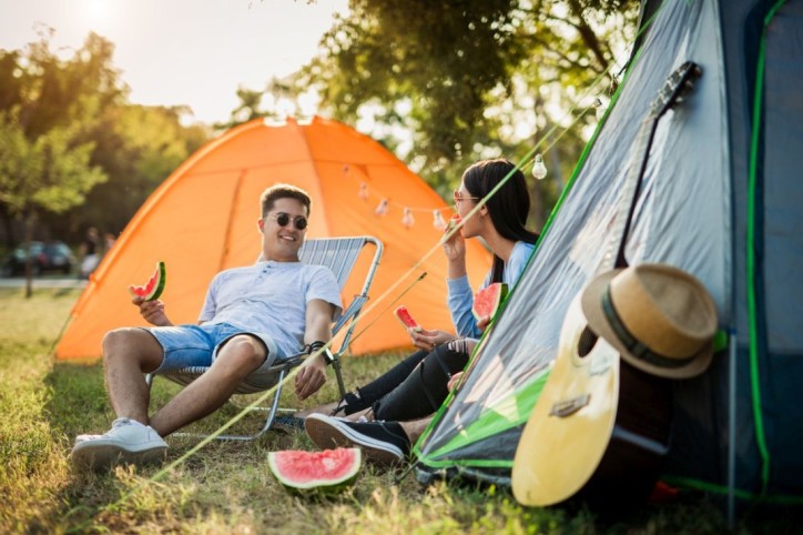 Ein junges Pärchen sitzt vor seinem Zelt auf einem Festival. 