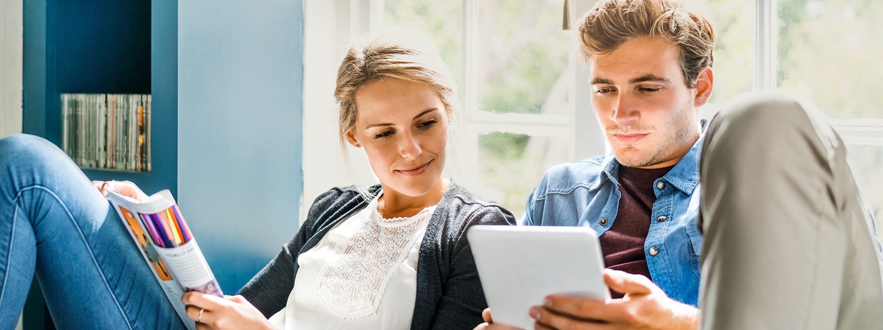 Eine circa 30-jährige Frau und ein circa 30-jähriger Mann schauen auf auf ein Tablet.