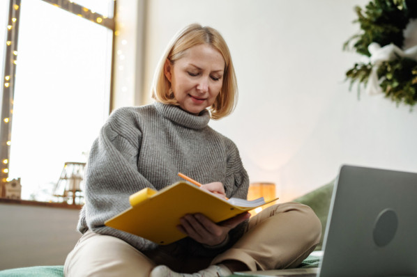 Eine reife Frau schreibt in ihr Dankbarkeits-Tagebuch