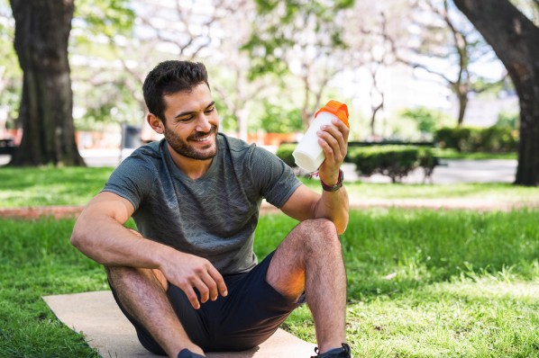 Sportler mit Eiweißdrink im Park