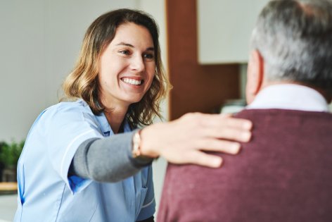Eine Pflegerin begrüßt freudig einen Patienten.