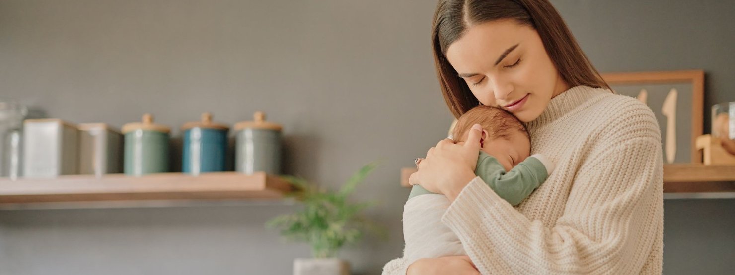 Eine junge Frau steht mit ihrem Baby in der Küche-