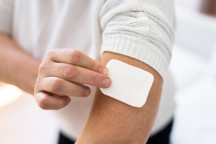 Woman Applying Patch On Her Arm At Home