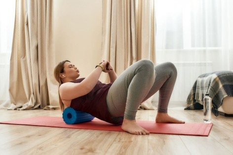 Eine junge Frau beim Faszientraining mit einer Fazsienrolle