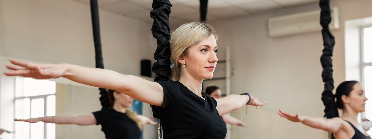 Eine junge Frau Anfang 20 nimmt an einer Bungee-Fitness-Kursstunde im Fitnessstudio teil.