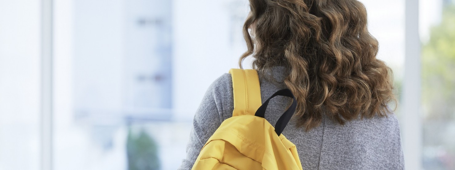 Ein ca. 14-jähriger Junge sitzt vor der schule auf einer Stufe und scha ut traurig auf sein Smartphone