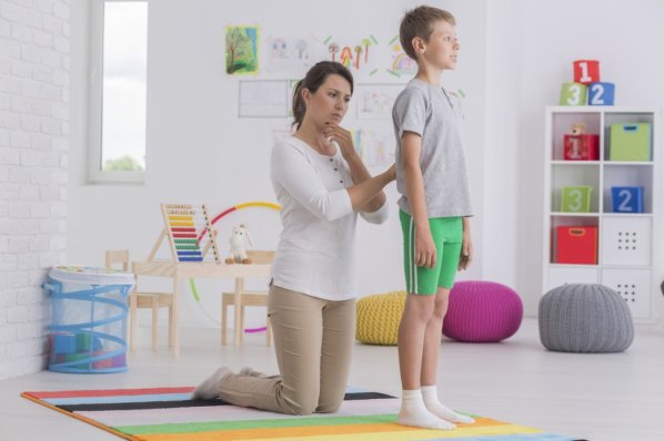 Eine Physiotherapeutin untersucht den Rücken eines Jungen