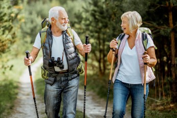 Älteres Paar beim Wandern mit Stöcken im Wald.