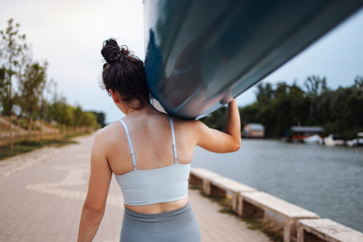 Eine Frau trägt ein Ruderboot