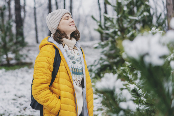 Junge Frau in gelber Jacke, die Luft im Winterwald atmet