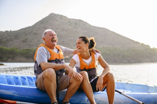 Vater und Tochter sitzen auf einem Boot am Strand. 