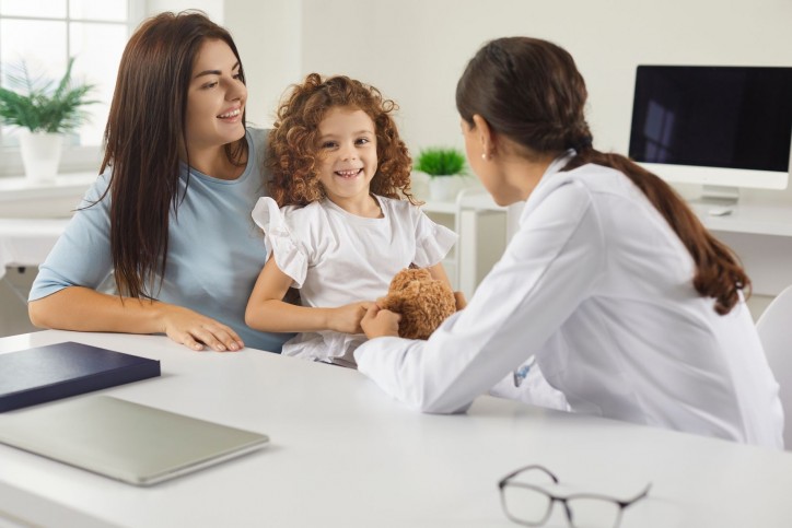 Eine Mutter sitzt mit ihrer Tochter bei einer Ärztin und lässt sich beraten. Alle lächeln.