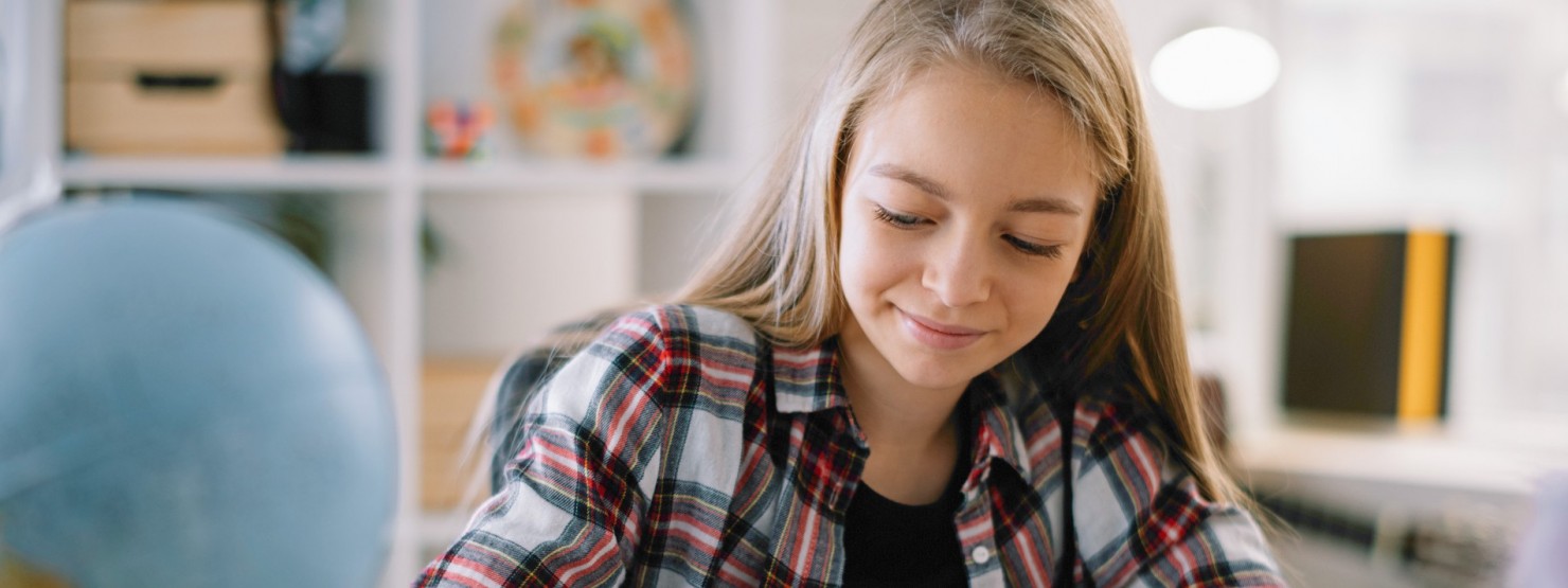 Mädchen schreibt zuhause in Heft